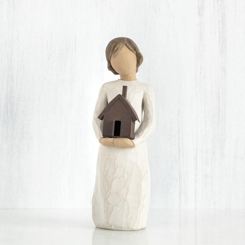 Mi Casa by Willow Tree. Standing figure in cream dress, holding dimensional metal house with chimney and open front door in her arms