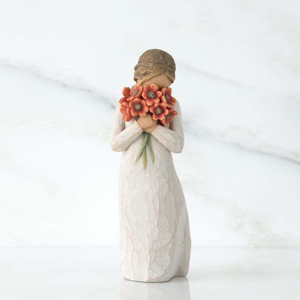 Standing figure in cream dress, holding large bouquet of red-orange poppies up to her face