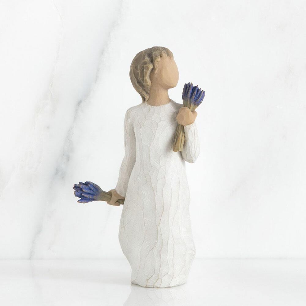 tanding female figure in cream dress, holding bundle of lavender flowers in one raised hand, and another bundle in other hand at her side