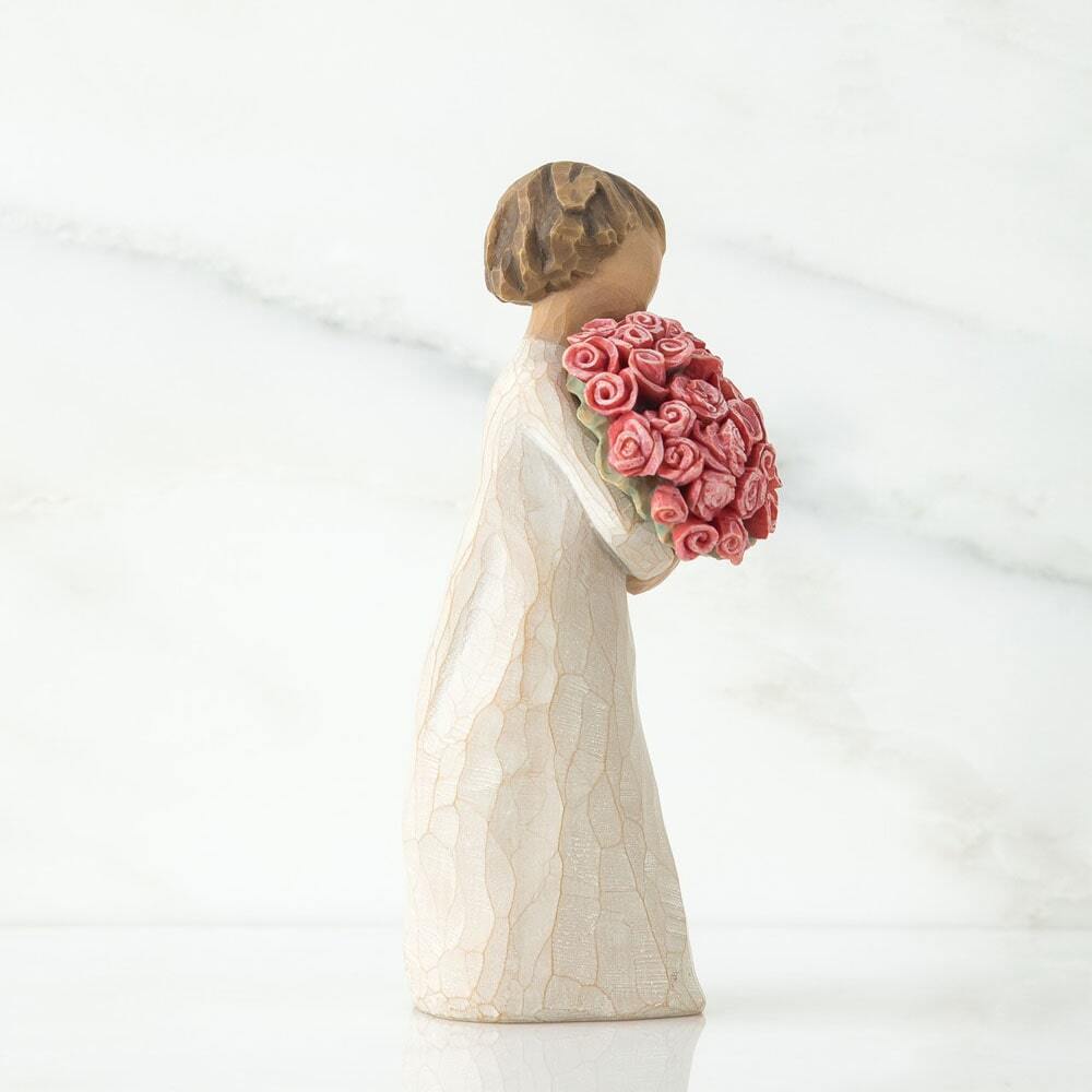 Standing female figure in cream dress holding large bouquet of pink roses