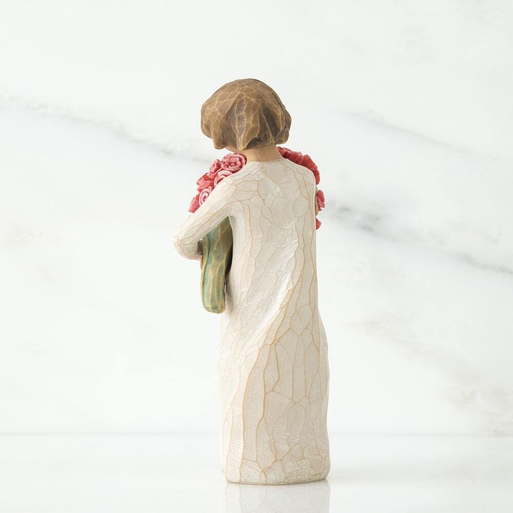 Standing female figure in cream dress holding large bouquet of pink roses