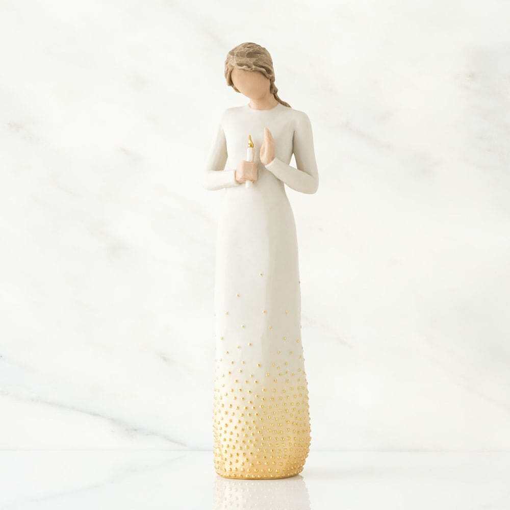 Standing figure in cream dress with elongated torso, holding candleholder with gold-leaf candle in her hands. Skirt of figure embellished with gold paint and gold-leaf dots